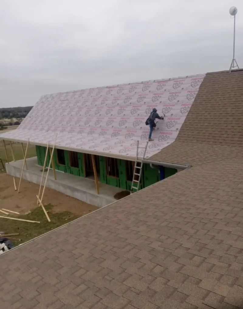 Worker preparing underlayment for a metal roof installation in South Weber